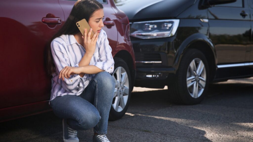 Stressed woman talking on a phone outdoors after a car accident